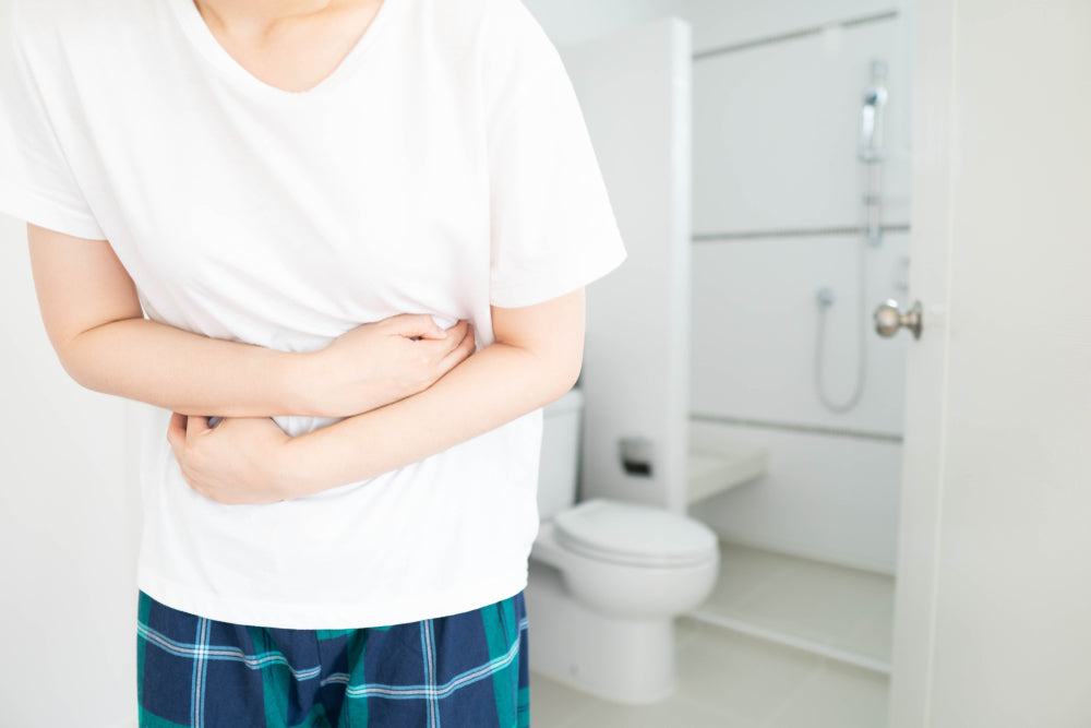 Woman suffering from irritable bowel syndrome (IBS) clutching stomach because of abdominal pain. 